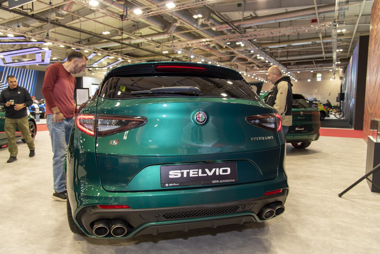Rear view of a green SUV with quad exhausts and taillights in a showroom