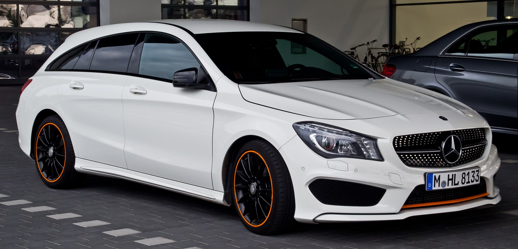 Side view of a white shooting brake with black wheels and orange rim accents
