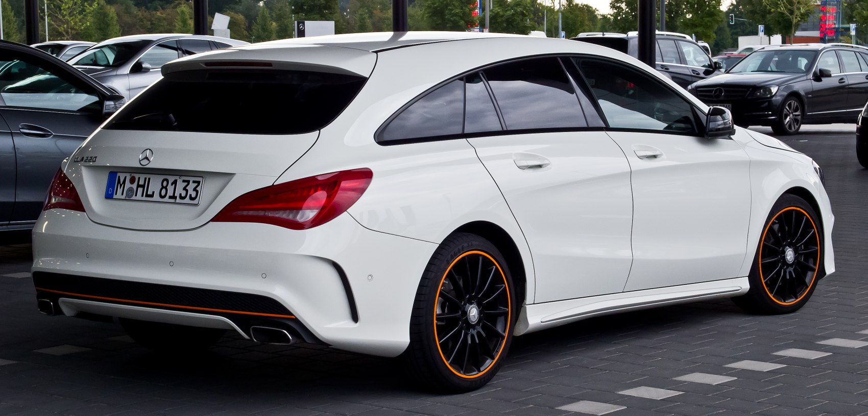 White station wagon with black sporty wheels and orange rim accents