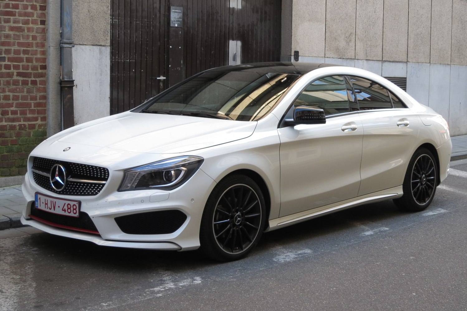 White sporty coupe with black wheels and aggressive front grille