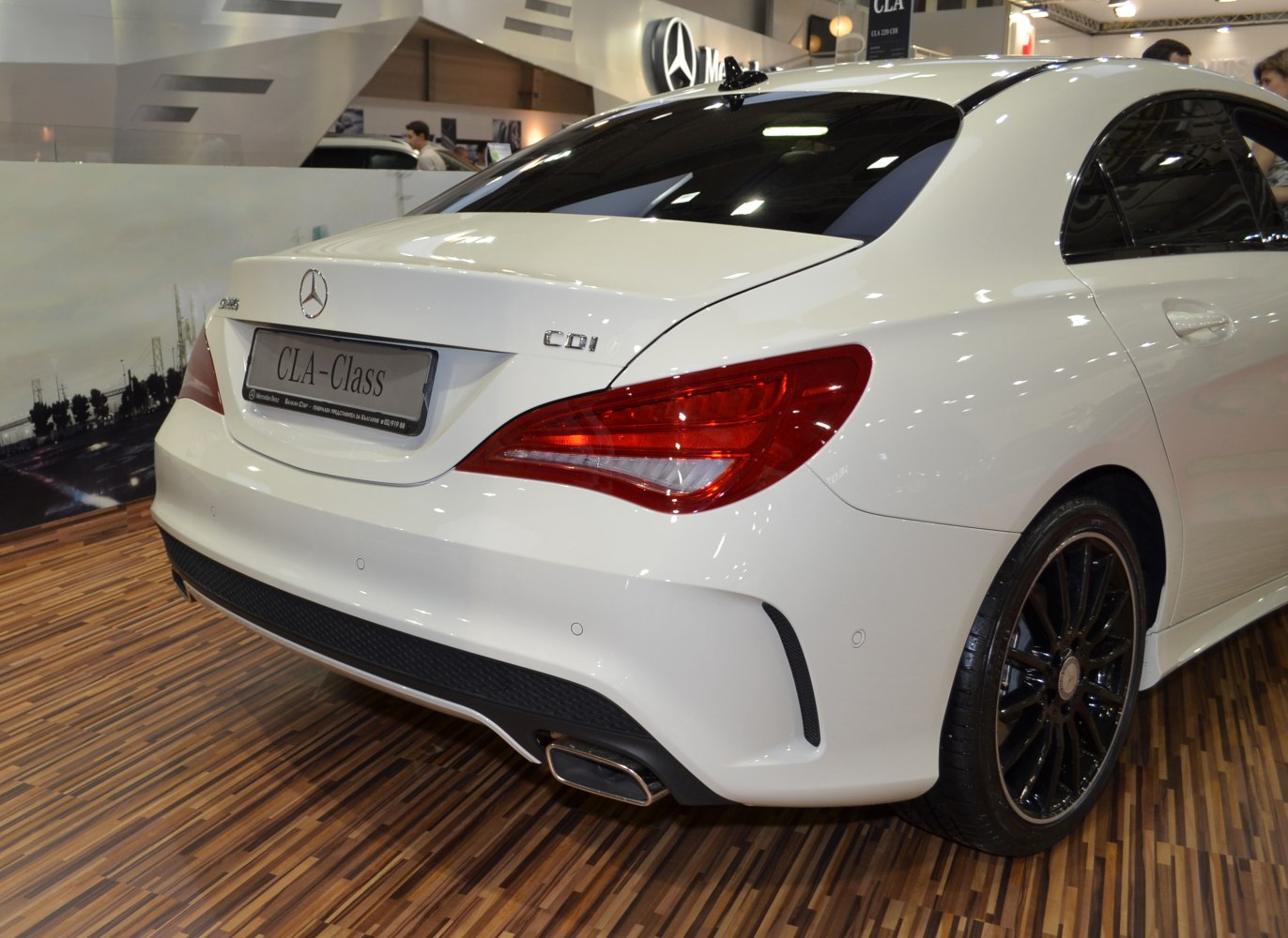 Close-up of rear taillights and exhaust of a white luxury coupe.