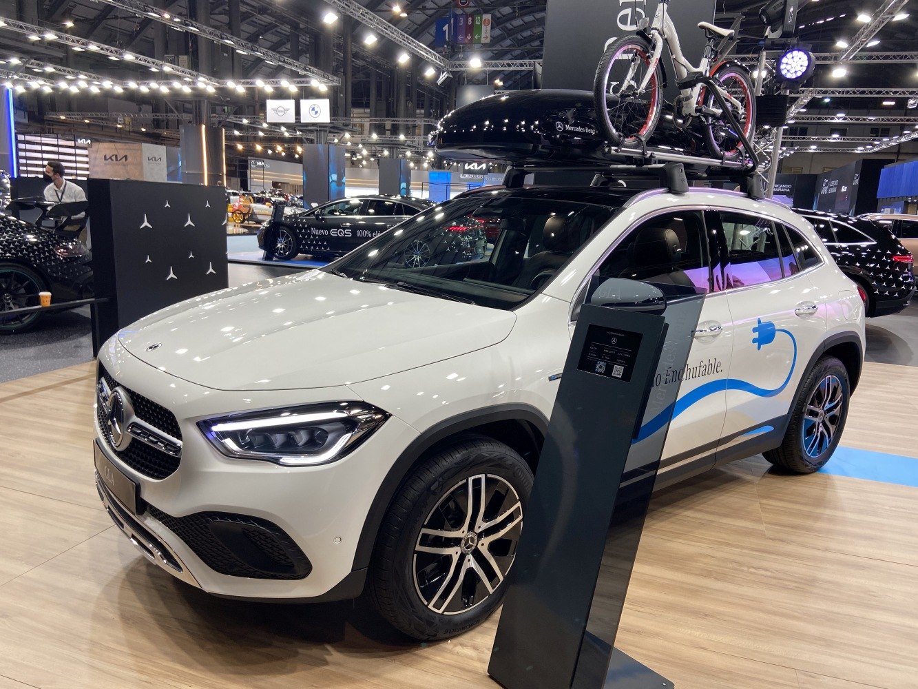 Electric SUV with roof bike carrier and nearby charging station