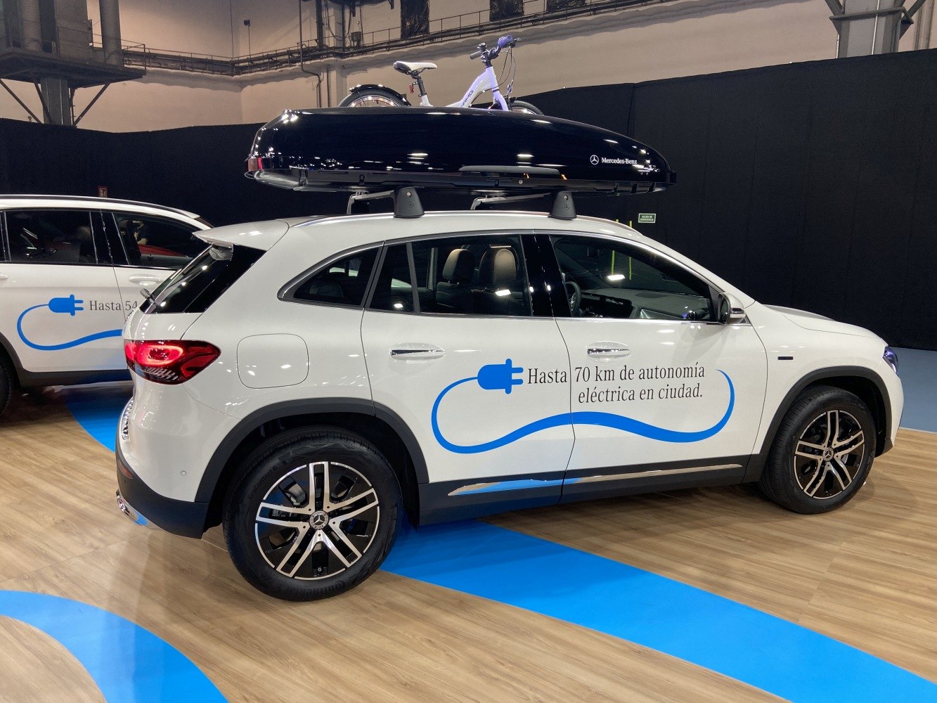 White electric SUV with roof cargo box and bicycle mounted on top