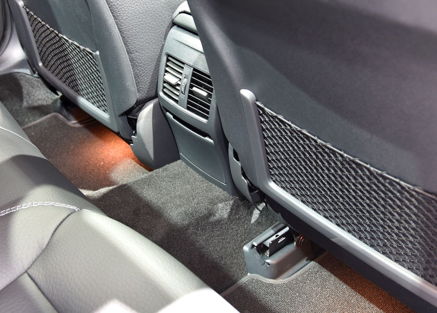 Rear seat air vents and storage nets with ambient lighting