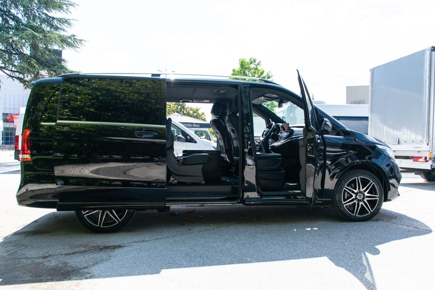 Black luxury multi-passenger van with open doors and alloy wheels