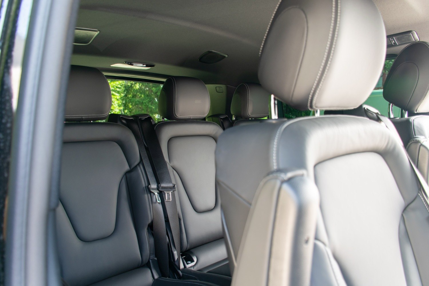 Black leather seats with adjustable headrests and seatbelts in spacious vehicle interior