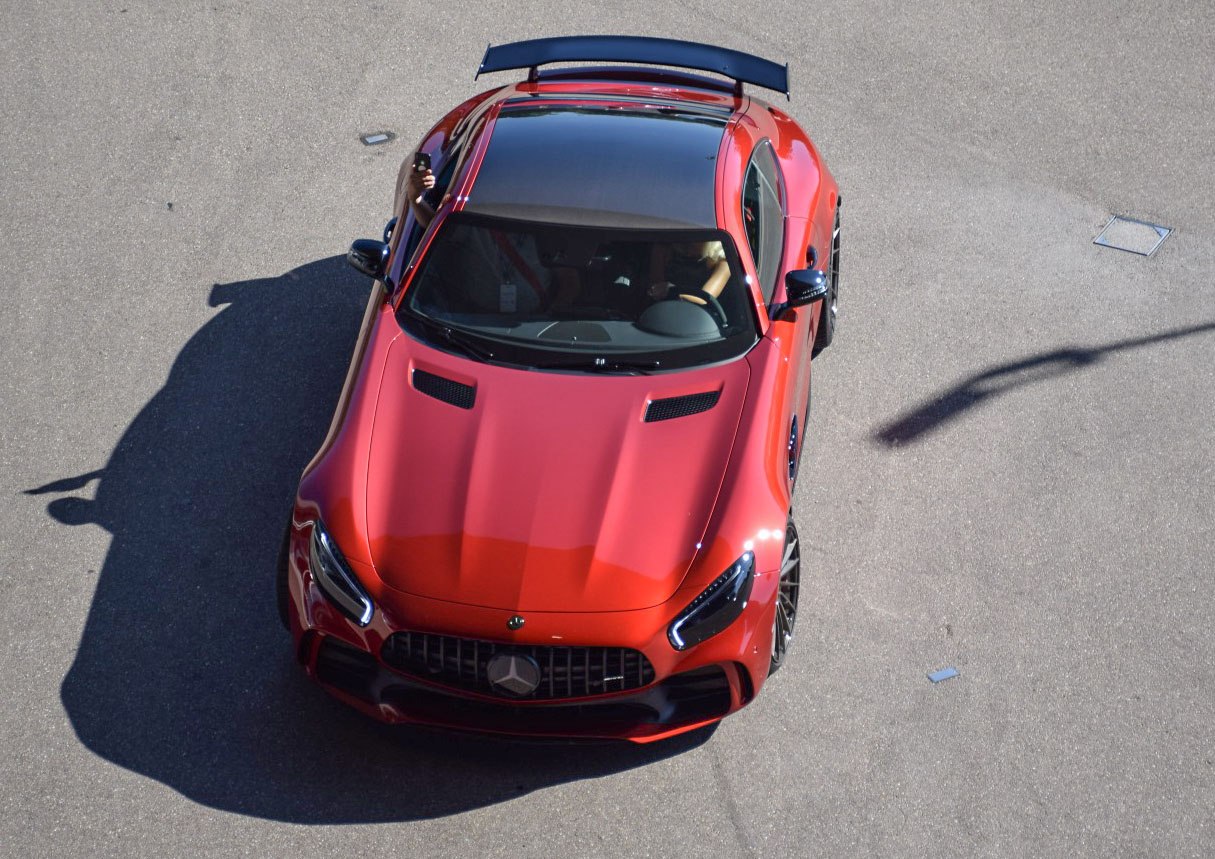 Red sports coupe with black roof and rear spoiler, aerial front view