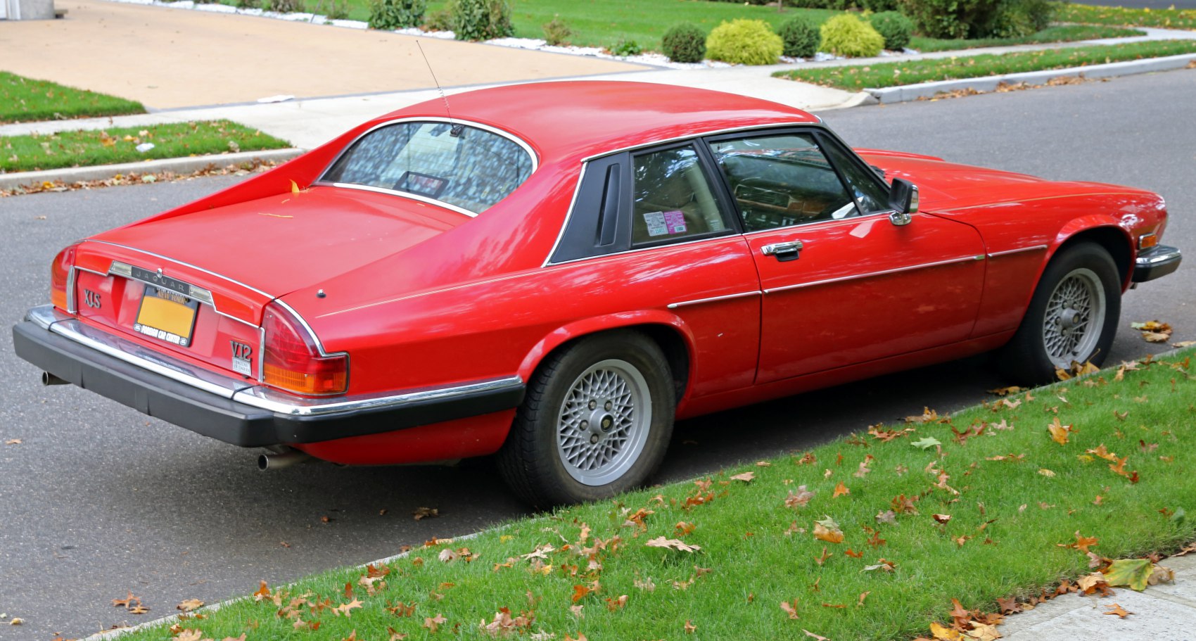Red classic coupe rear side with wire-spoke wheels and V12 badge