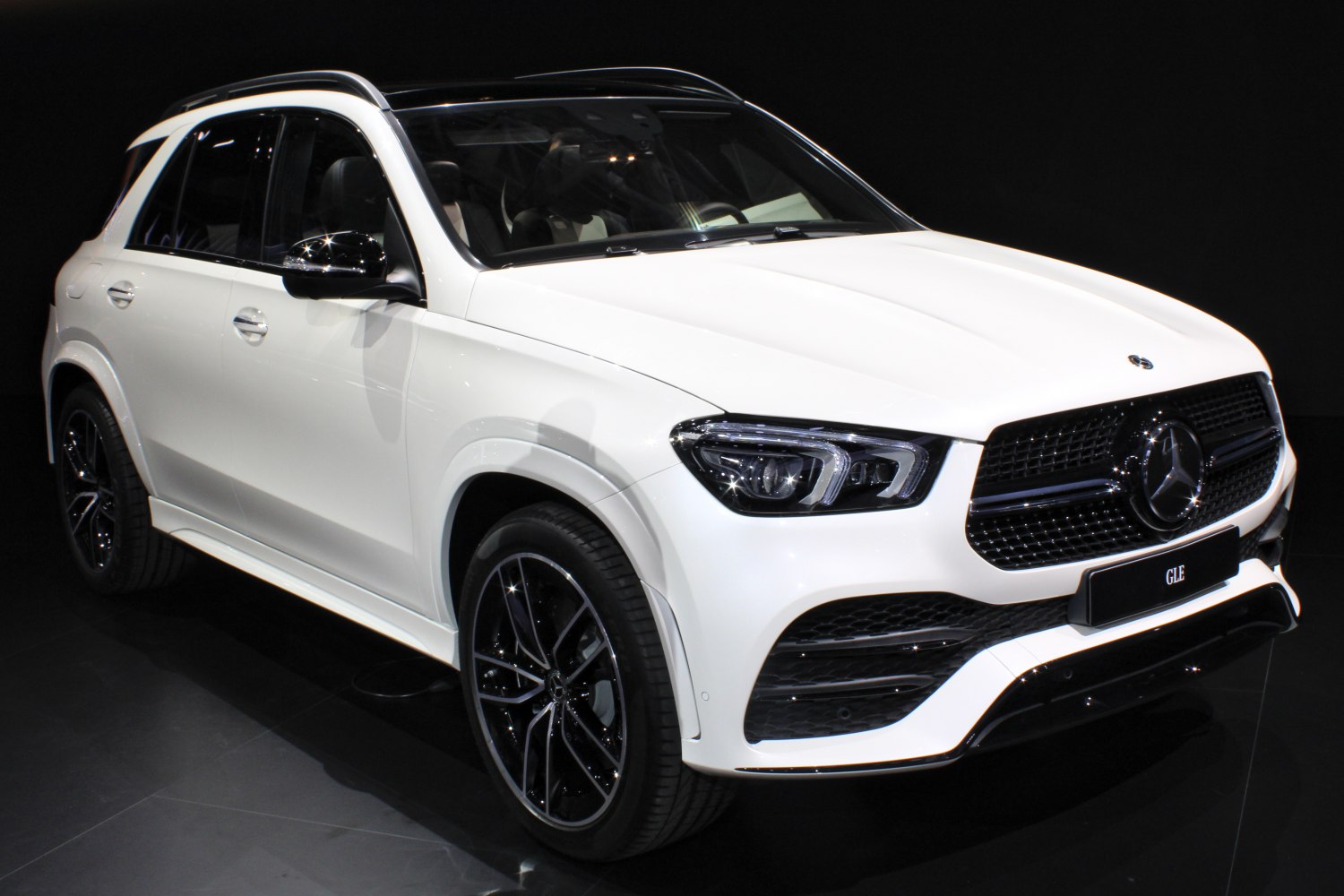 Angular front view of white luxury SUV with modern headlights and grille