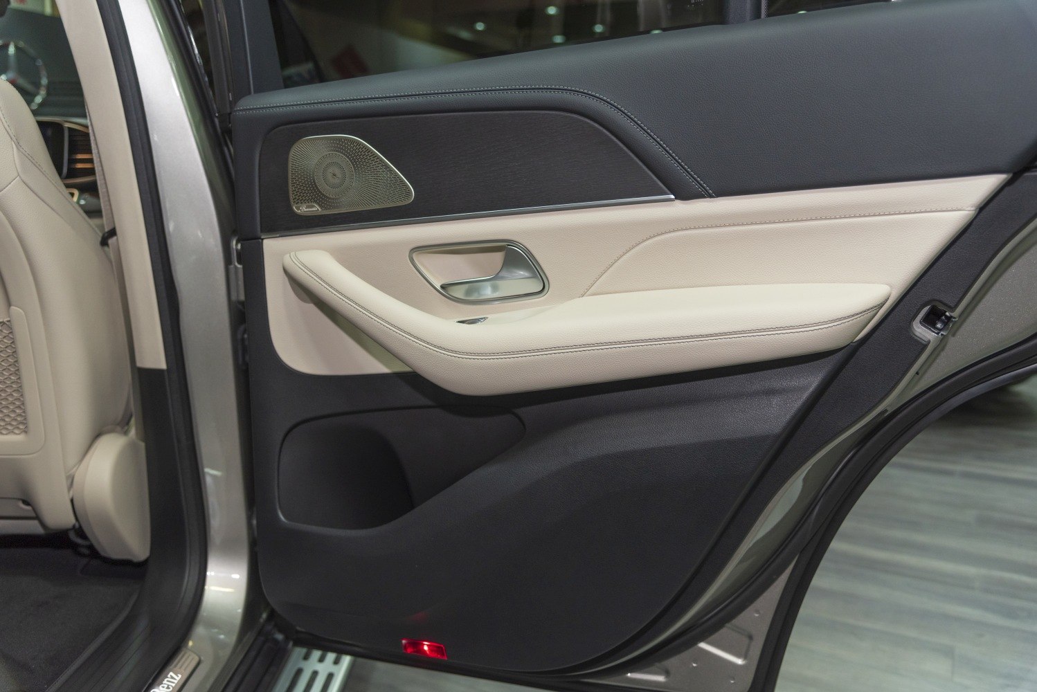 Rear interior door panel with beige leather and integrated speaker grille.