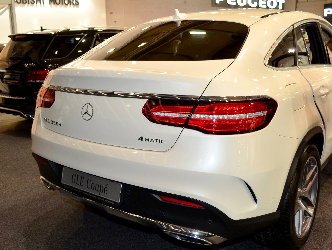 Rear view of a white SUV coupe with LED tail lights and dual exhaust