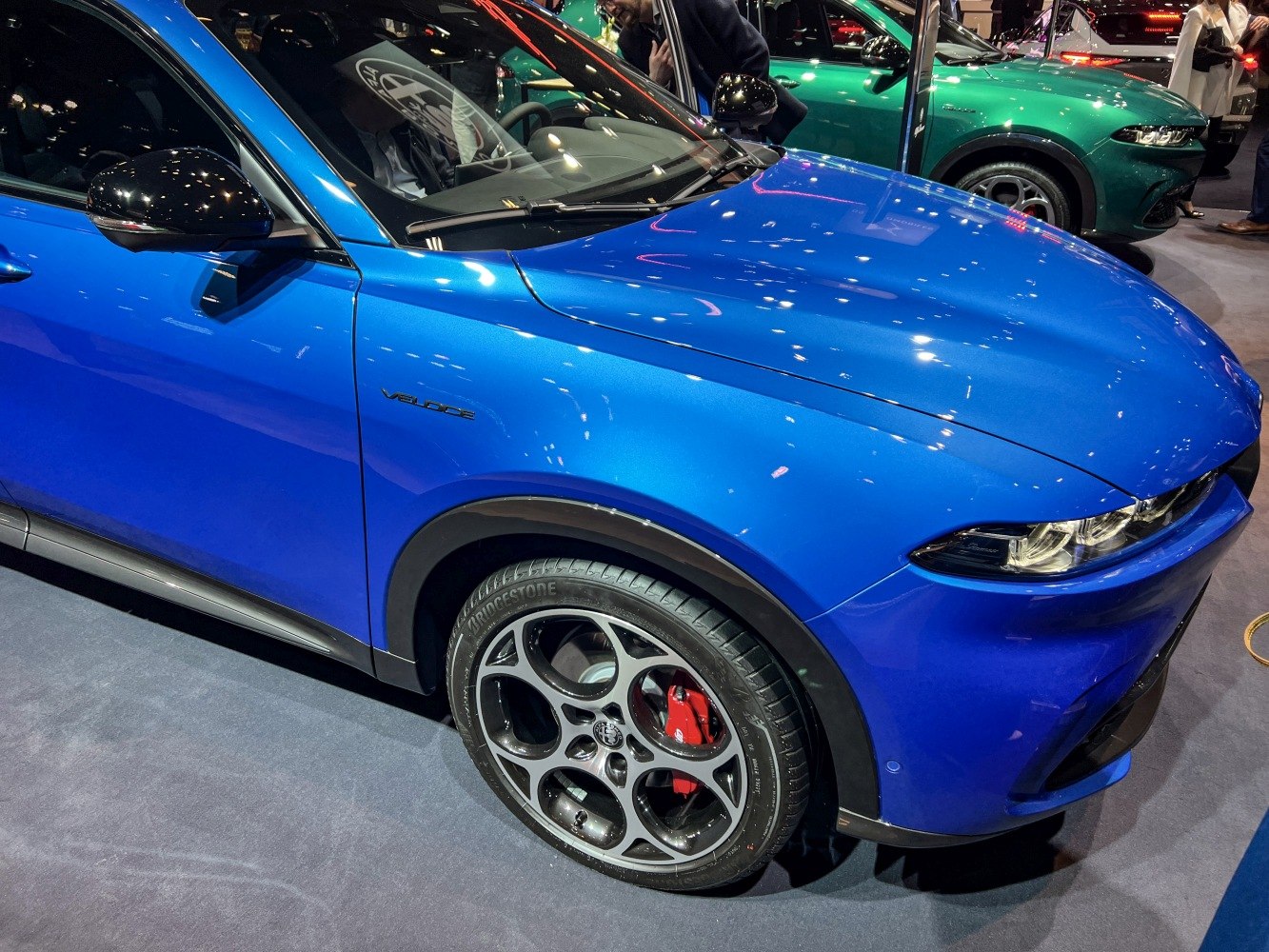 Front headlight and five-hole alloy wheel with red brake calipers.