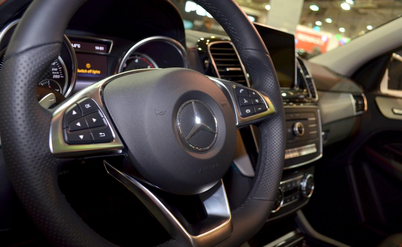 Close-up on Mercedes-Benz style steering wheel and dashboard controls