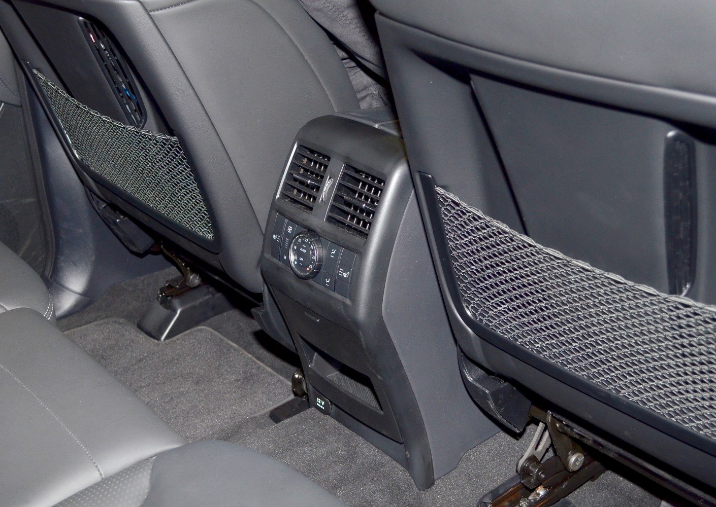 Rear seat air conditioning vents and climate control panel with storage nets