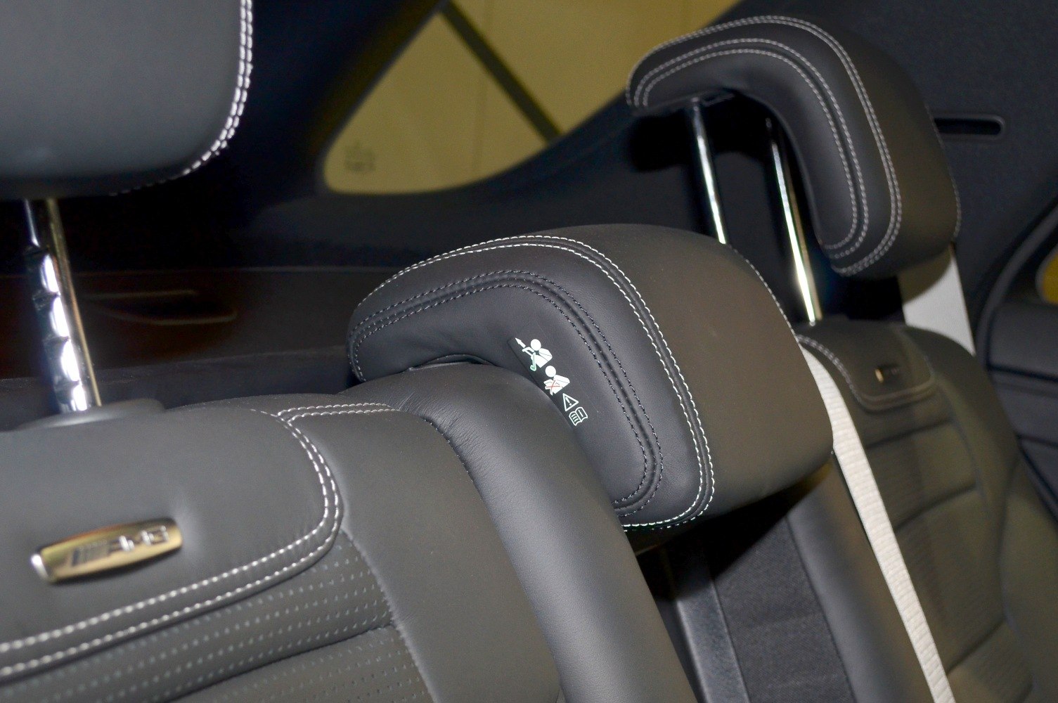 Luxury leather rear seat headrests with white stitching and safety warning labels