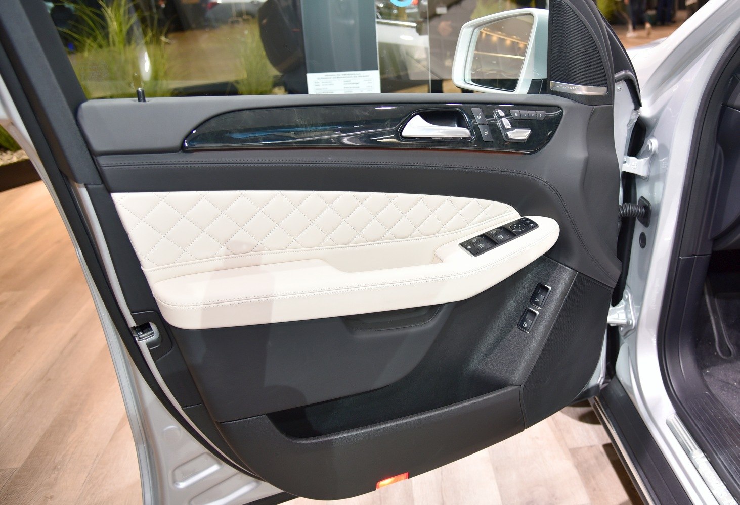 Diamond-stitched leather door panel with controls and handle