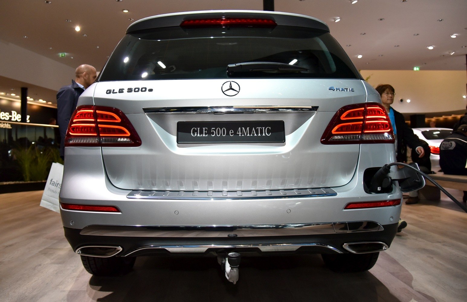Rear view of SUV with illuminated taillights and electric charging port.