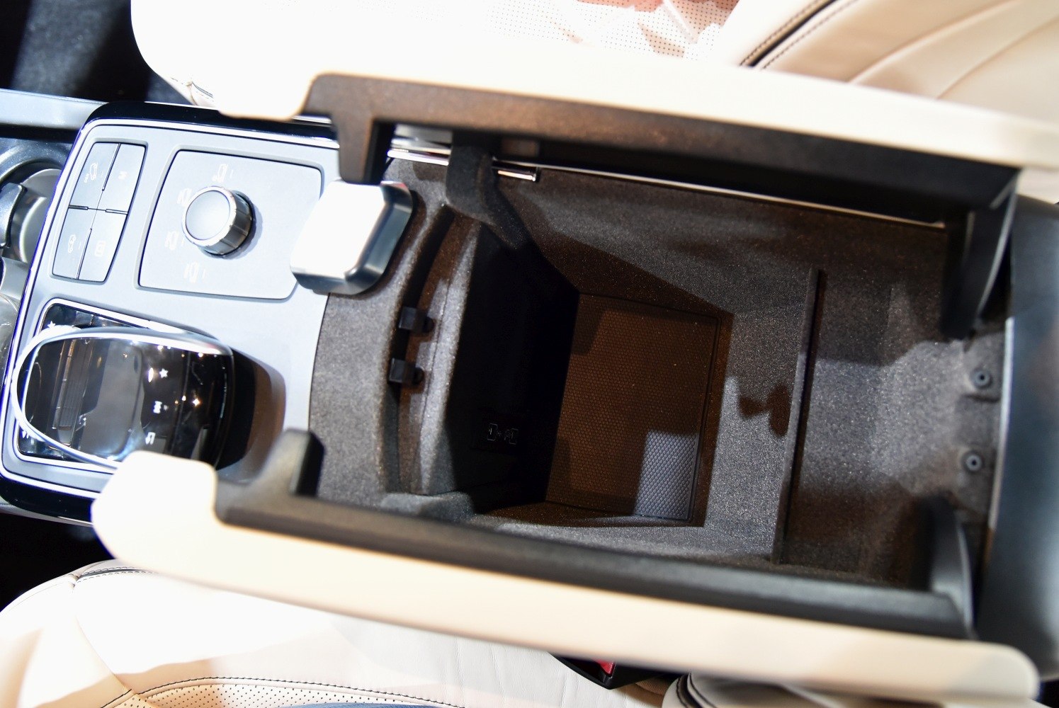 Center console storage compartment and control panel with knob and buttons.