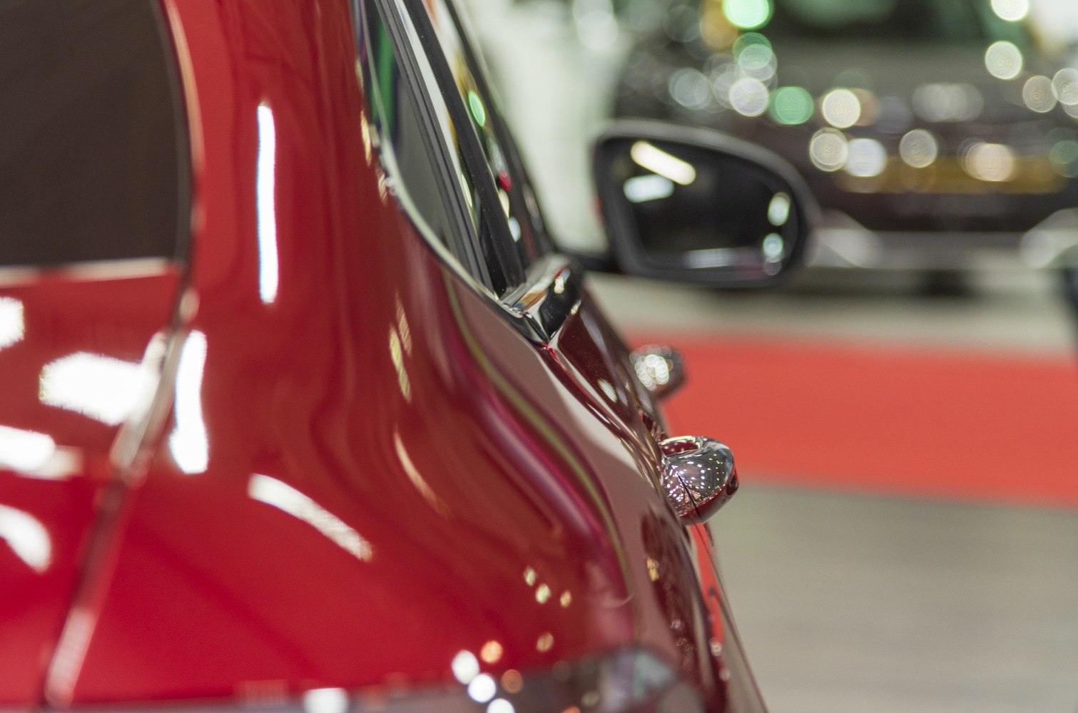Red luxury SUV coupe rear side door with sleek trim and side mirror.