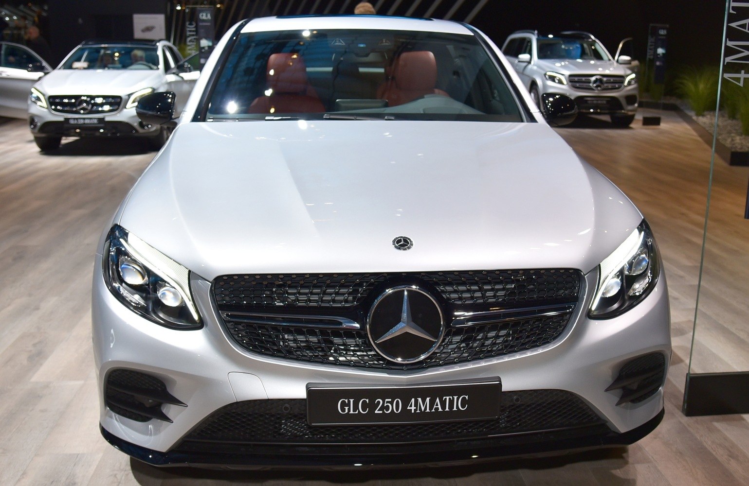Close-up of front grille with emblem and LED headlights on luxury SUV coupe.