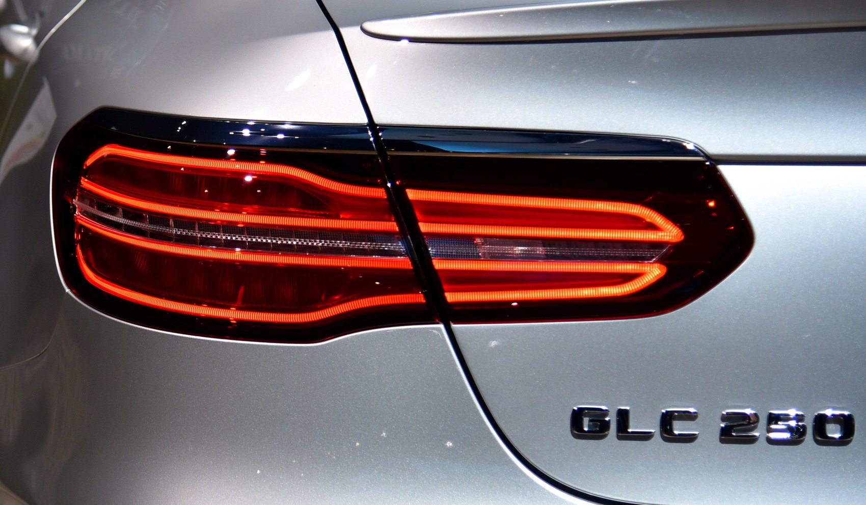 Closeup of LED rear tail light and model badge on vehicle's silver body