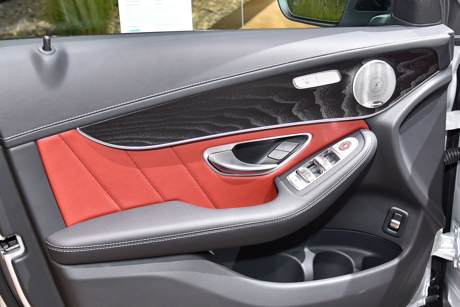 Luxury interior door panel with leather, wood trim, and control switches