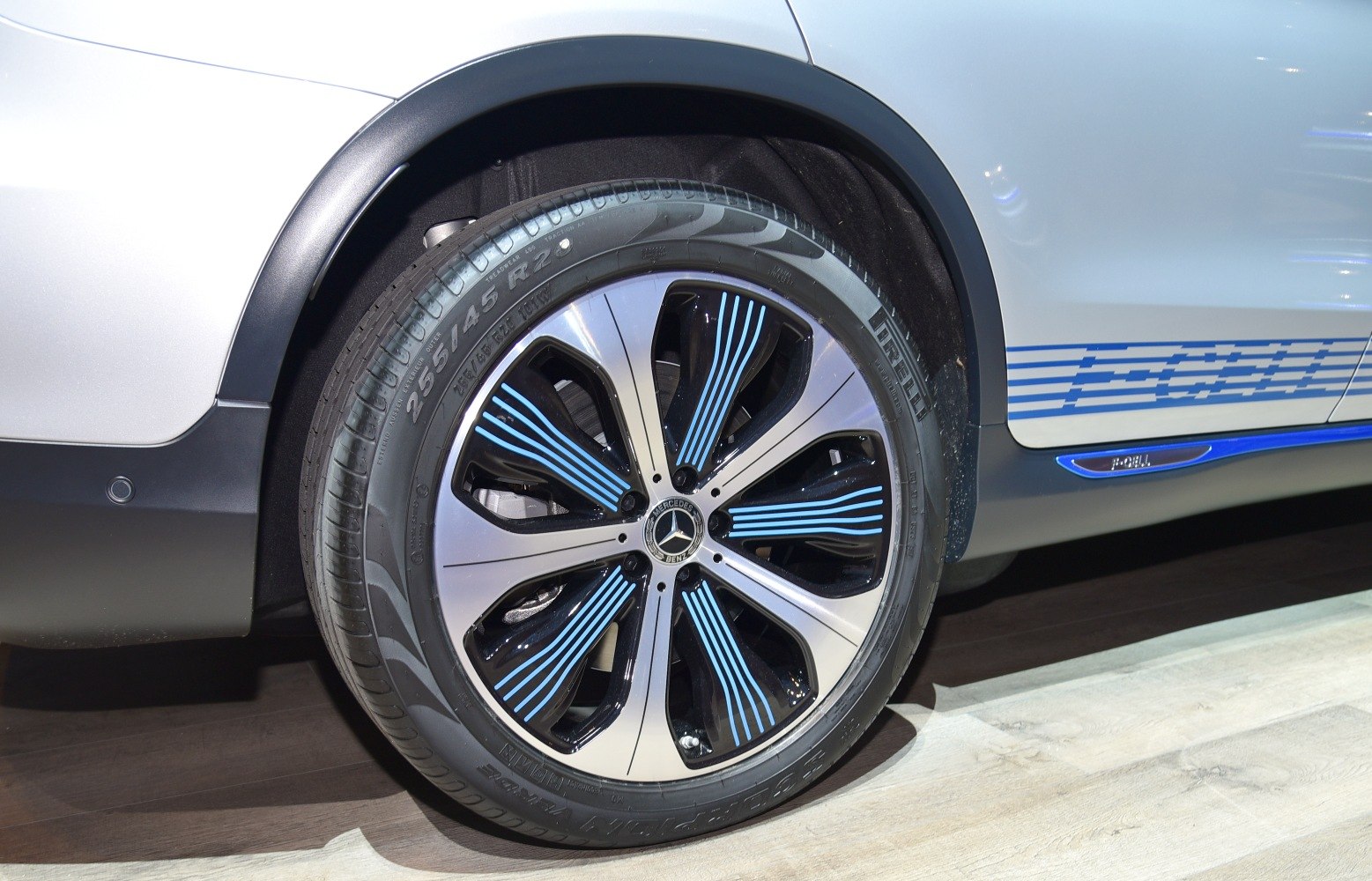 Close-up of alloy wheel with blue accents and Pirelli tire on SUV side panel with blue stripes