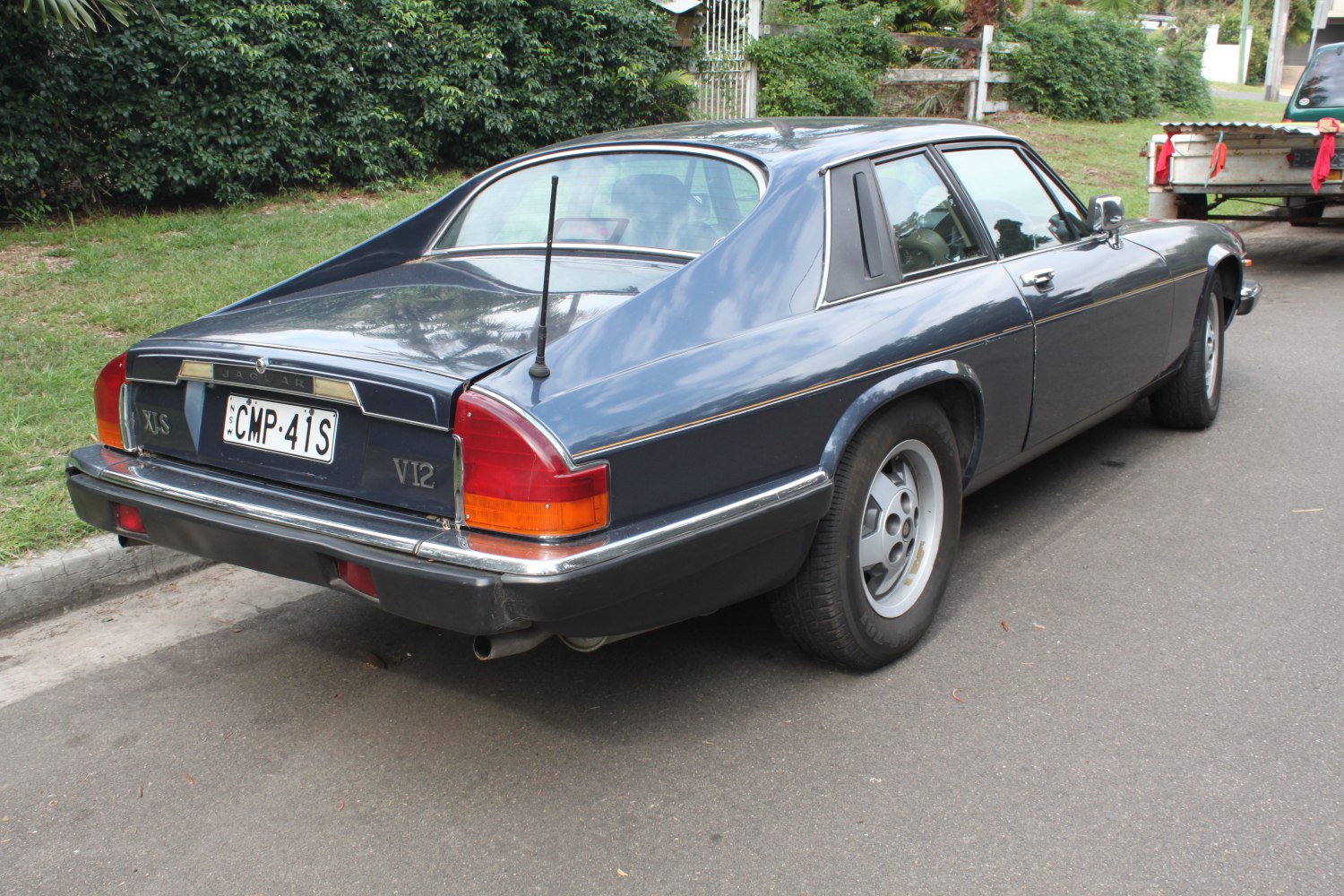 Rear view of classic coupe with V12 badging and distinctive tail lights
