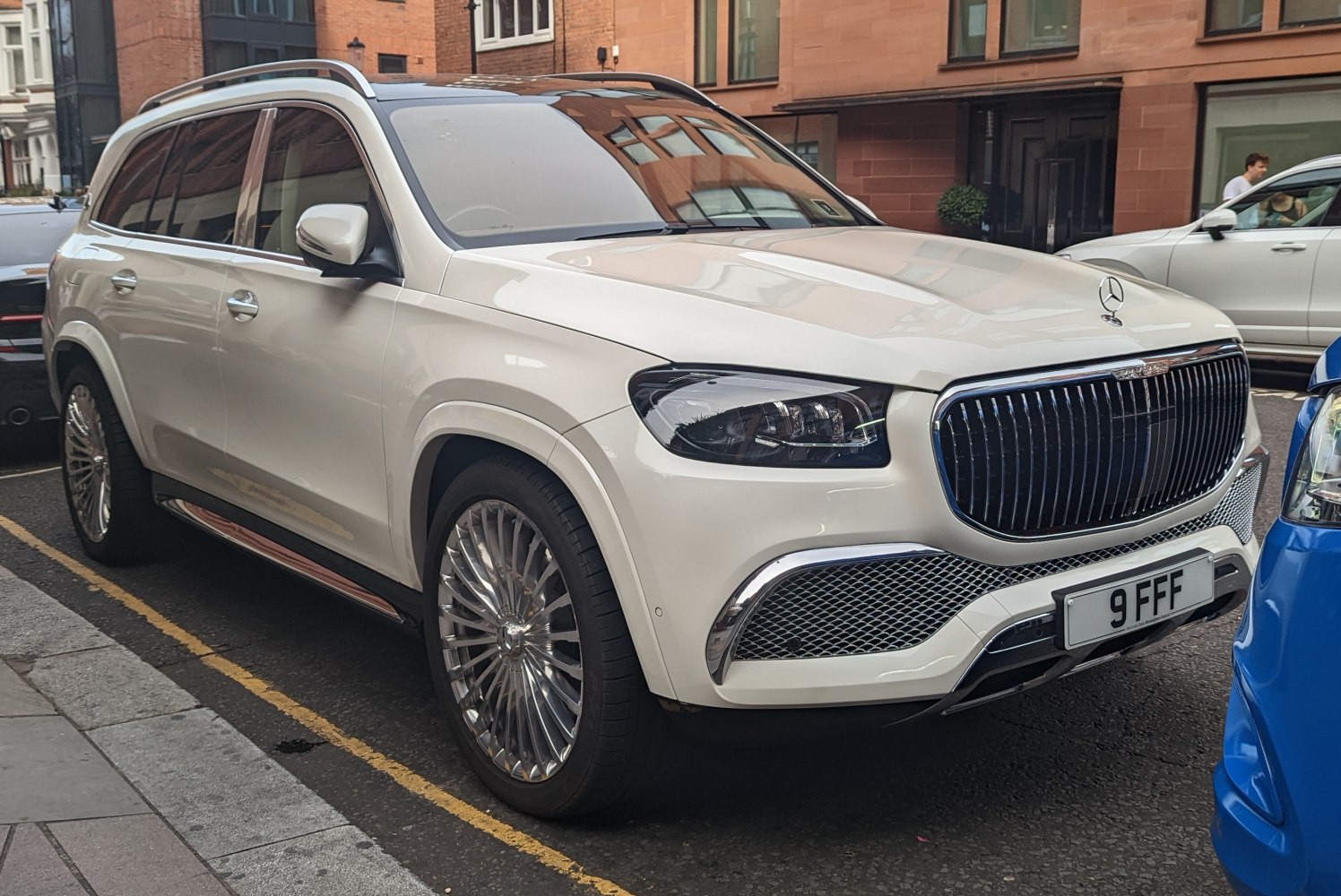 Prominent vertical bar front grille and multi-spoke alloy wheels on a white luxury SUV