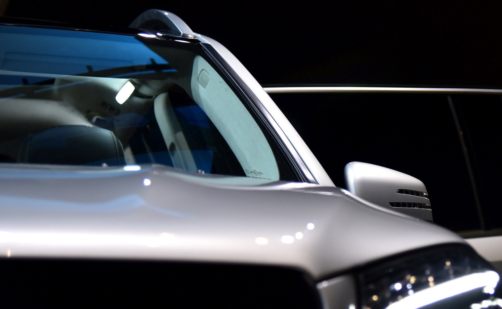 Close-up of side mirror and windshield with glossy paint and LED headlight detail