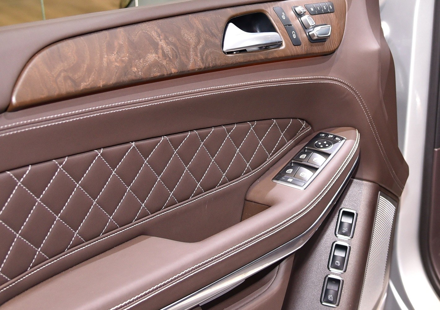 Brown leather door panel with wood trim and control buttons