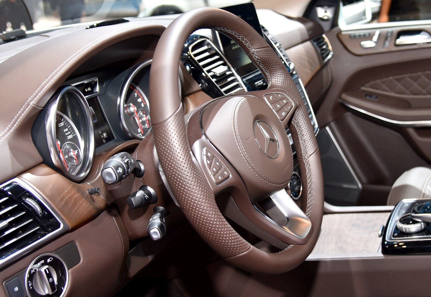 Brown leather steering wheel with perforated grip and detailed dashboard.