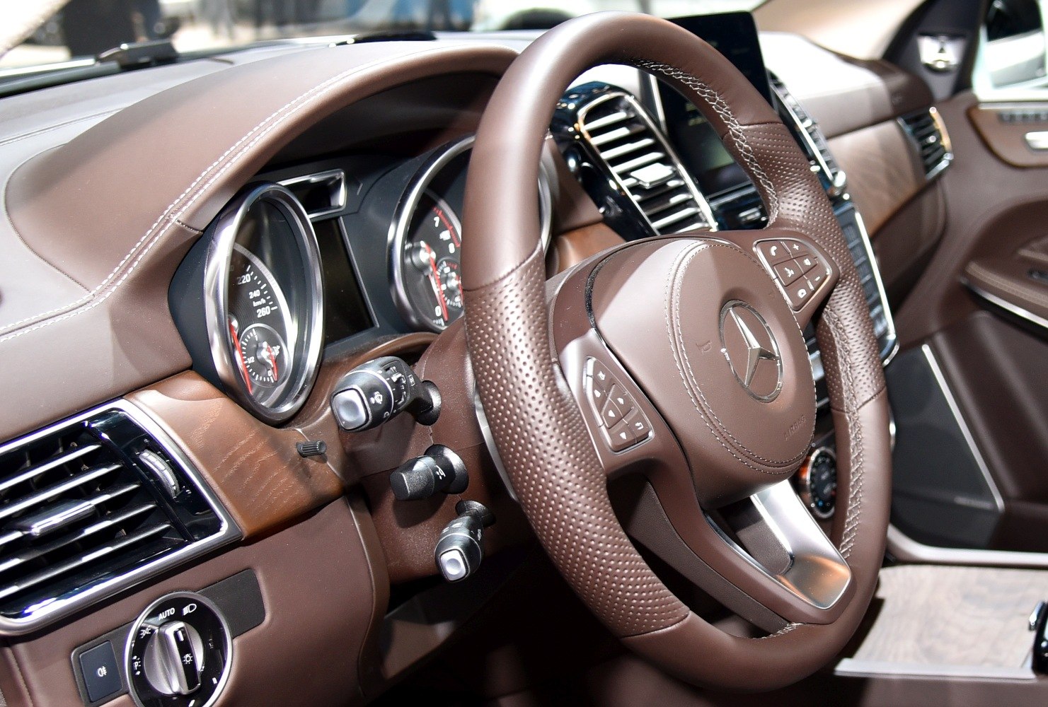 Brown perforated leather steering wheel and luxury dashboard controls.