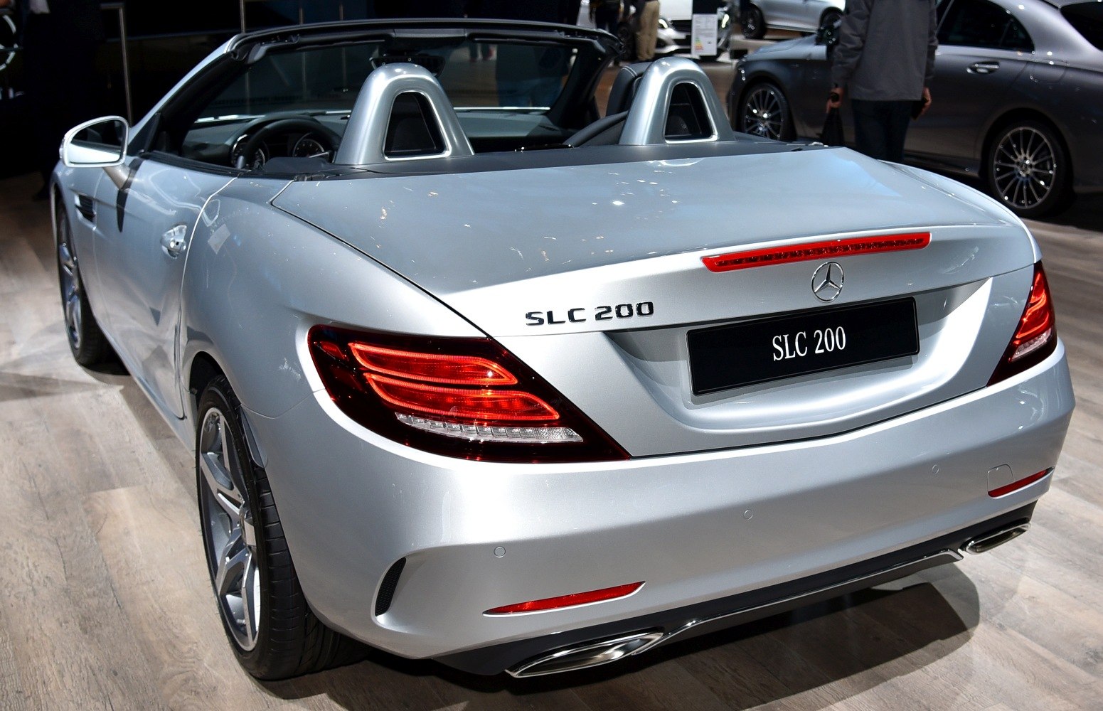 Rear view of a silver convertible with distinctive taillights and dual exhaust