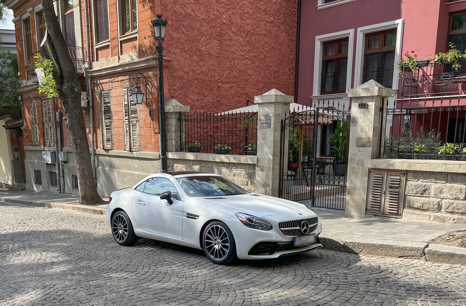 White sleek coupe with modern grille and alloy wheels on cobblestone street