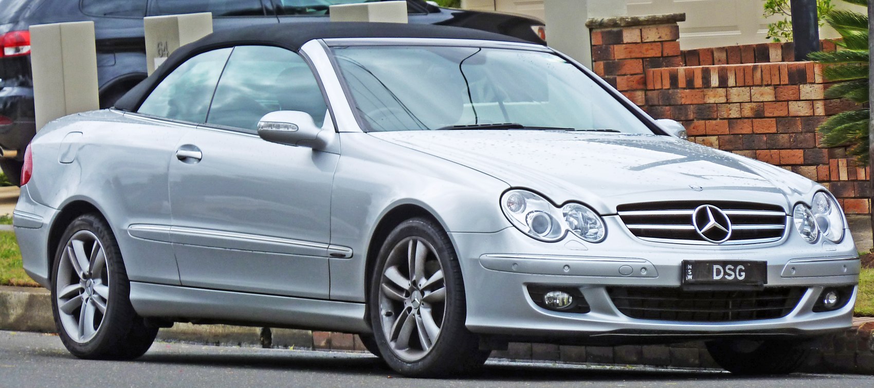 Silver convertible with black soft top, distinctive headlights, and alloy wheels