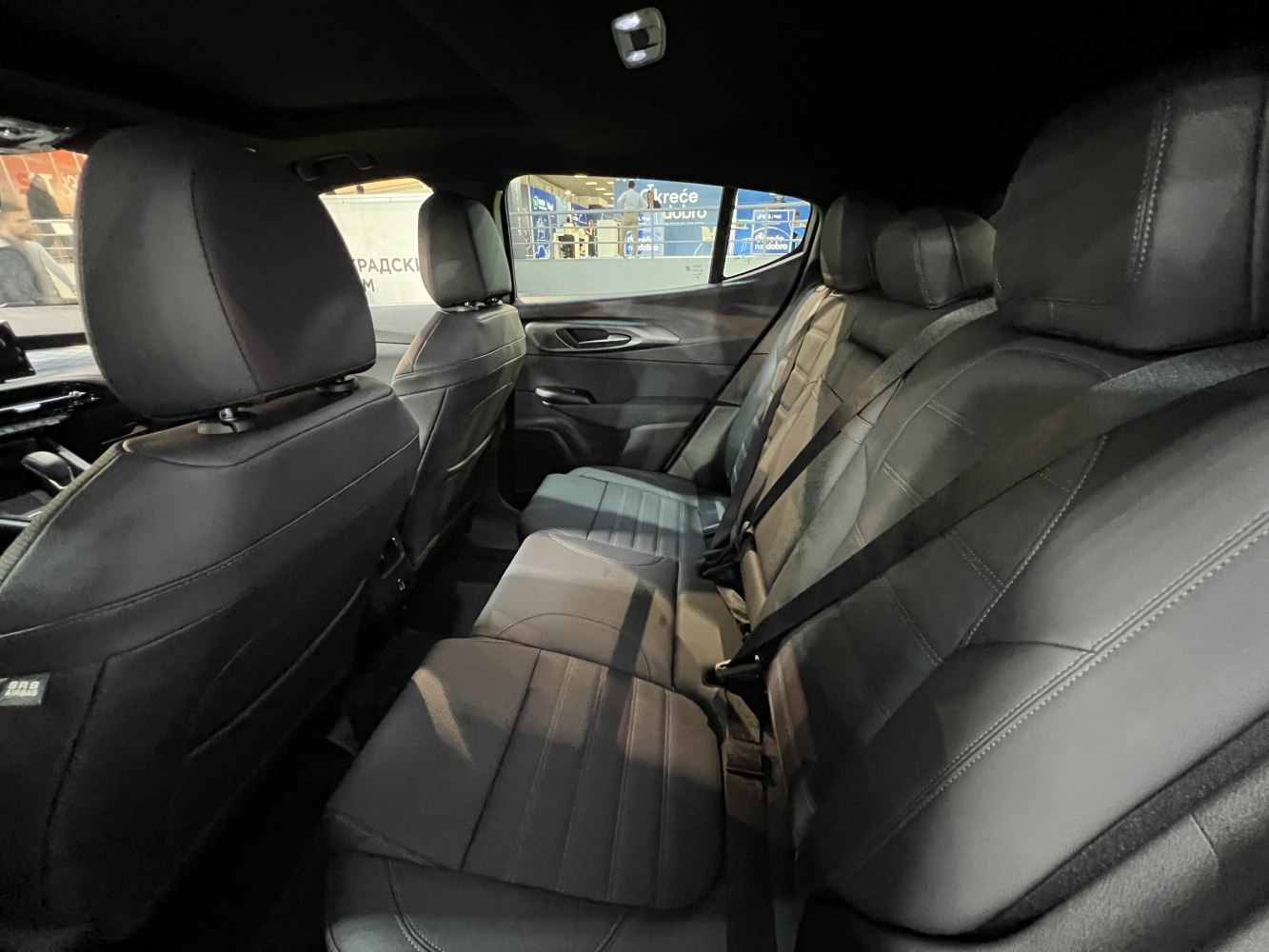 Rear seating area with black leather upholstery and seat belts.