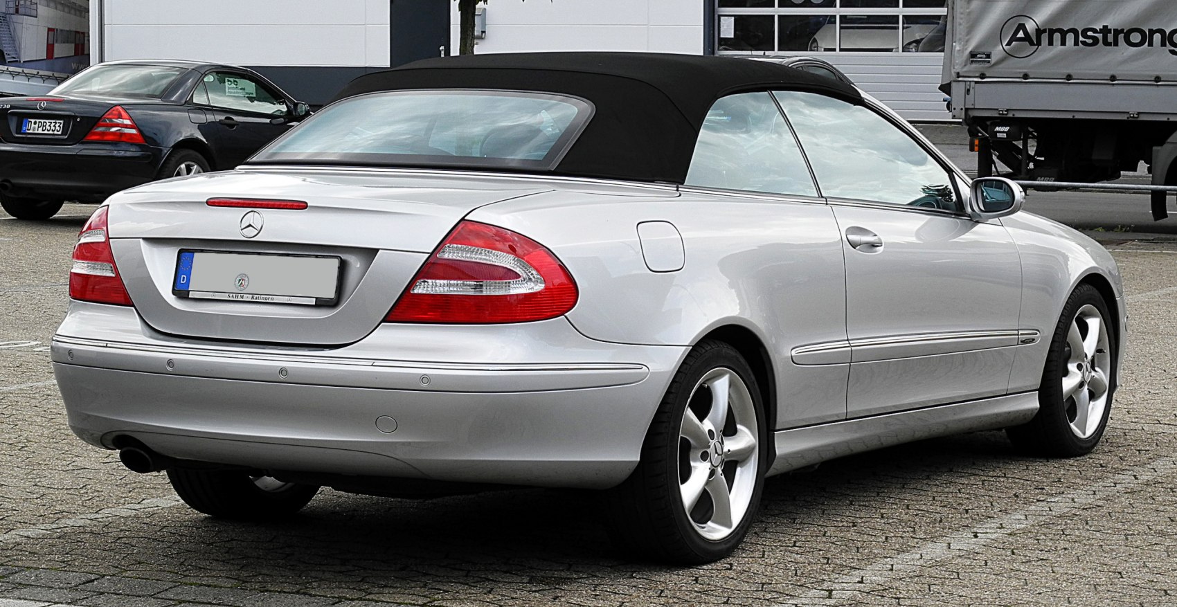 Rear and side view of silver convertible with black soft top and alloy wheels