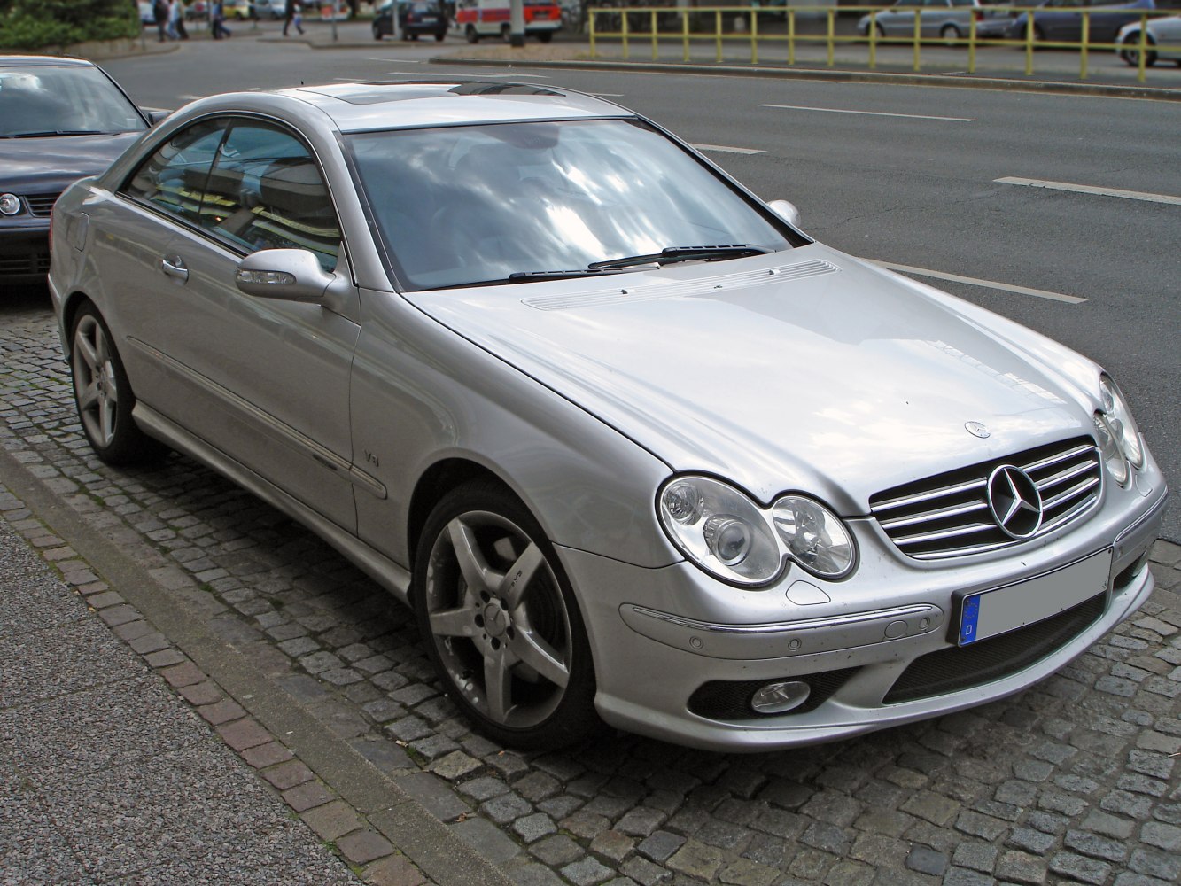 Front-side view of coupe with quad round headlights and chrome grille