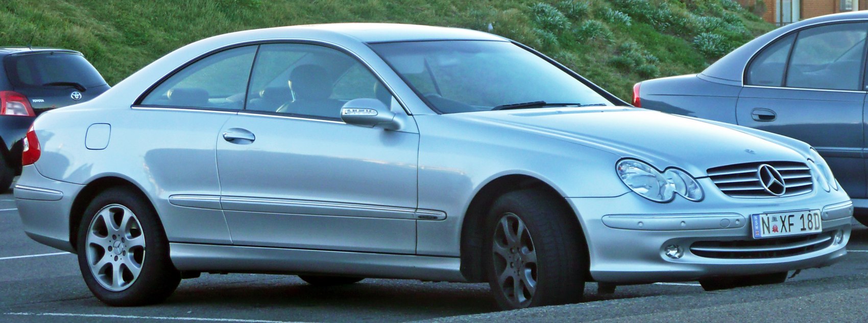 Silver two-door coupe with dual round headlights and alloy wheels
