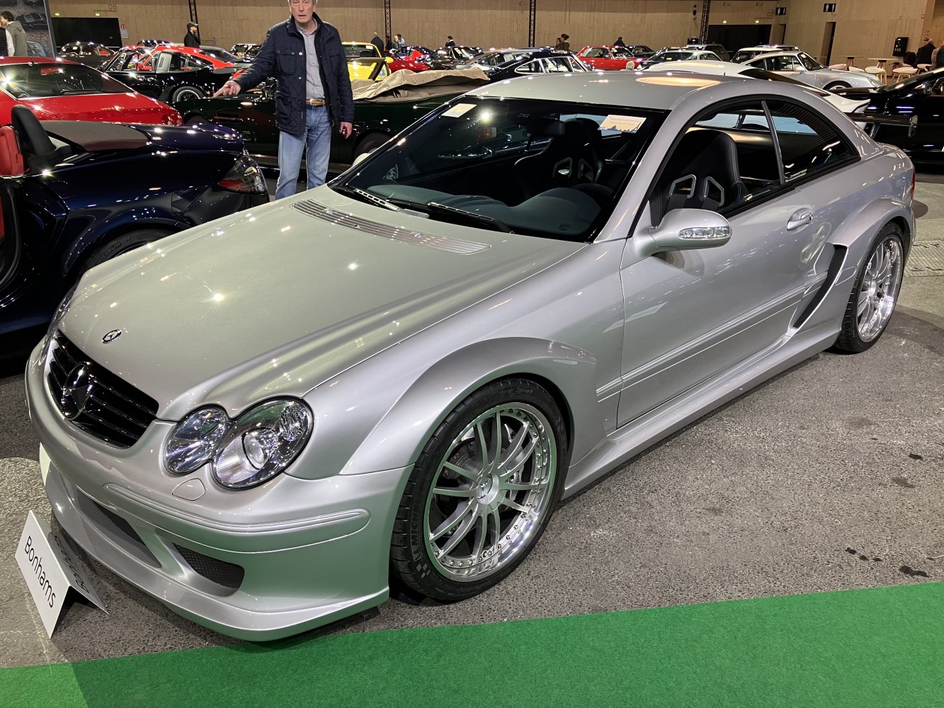 Wide-body silver coupe with quad oval headlights and aggressive aerodynamic features