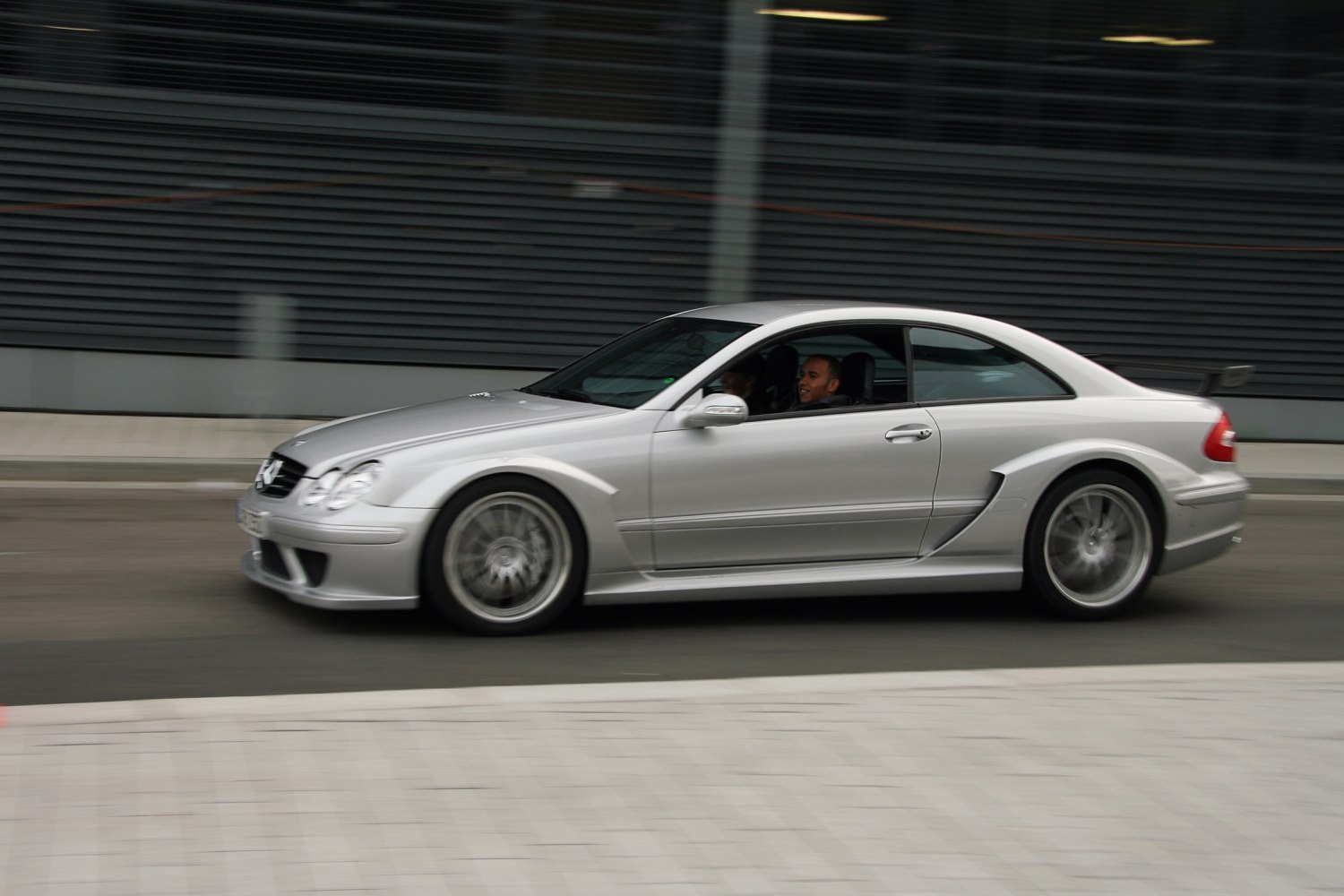 Silver two-door coupe with rear spoiler driving fast