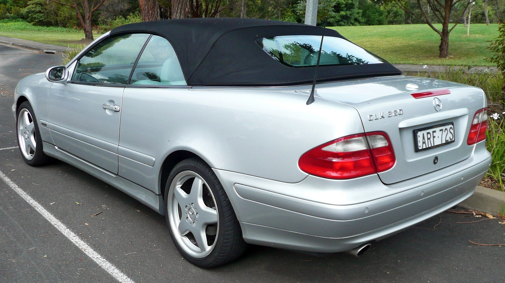 Convertible with black soft top and silver body in rear view
