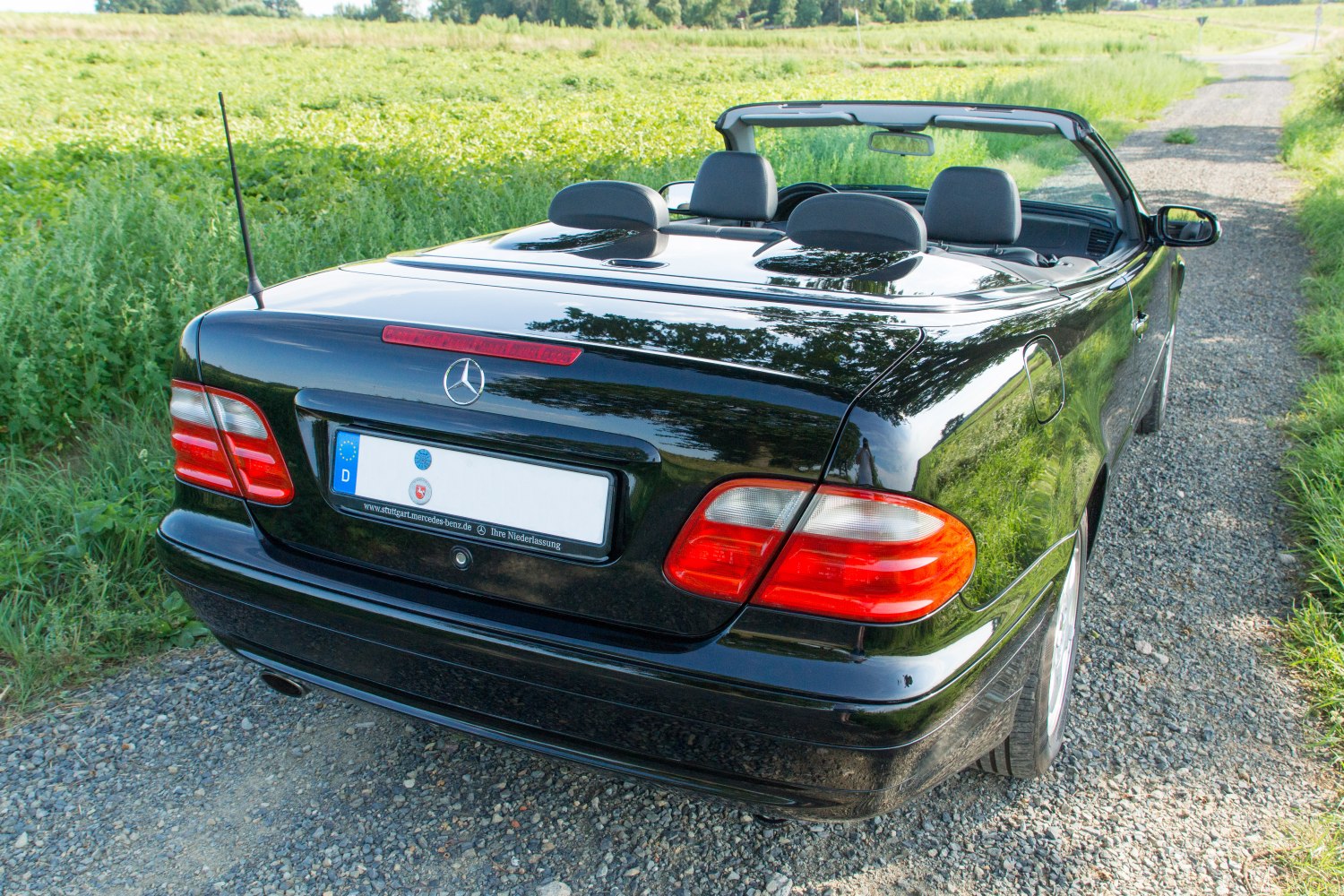 Rear view of a black convertible with distinctive taillights and open roof