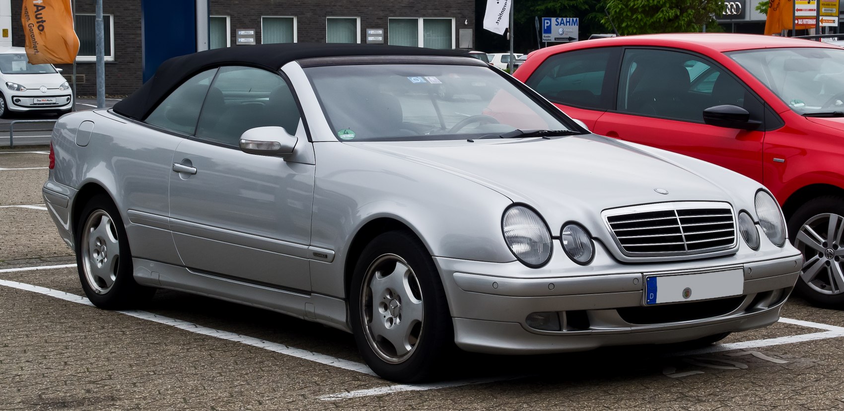 Silver convertible with black soft top and distinctive round headlights