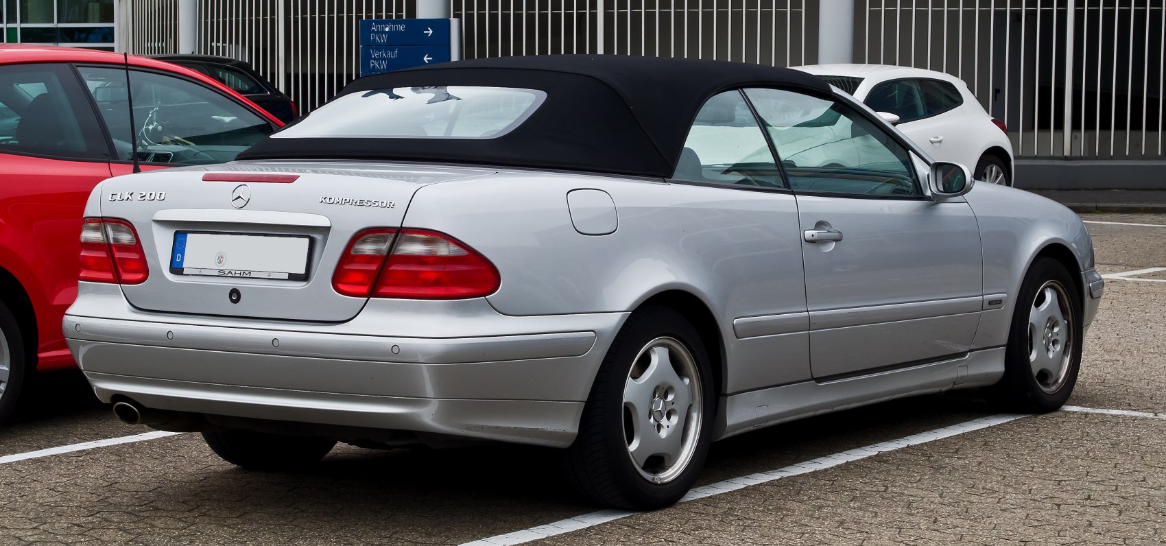 Rear-side view of a silver convertible with soft top and classic taillights