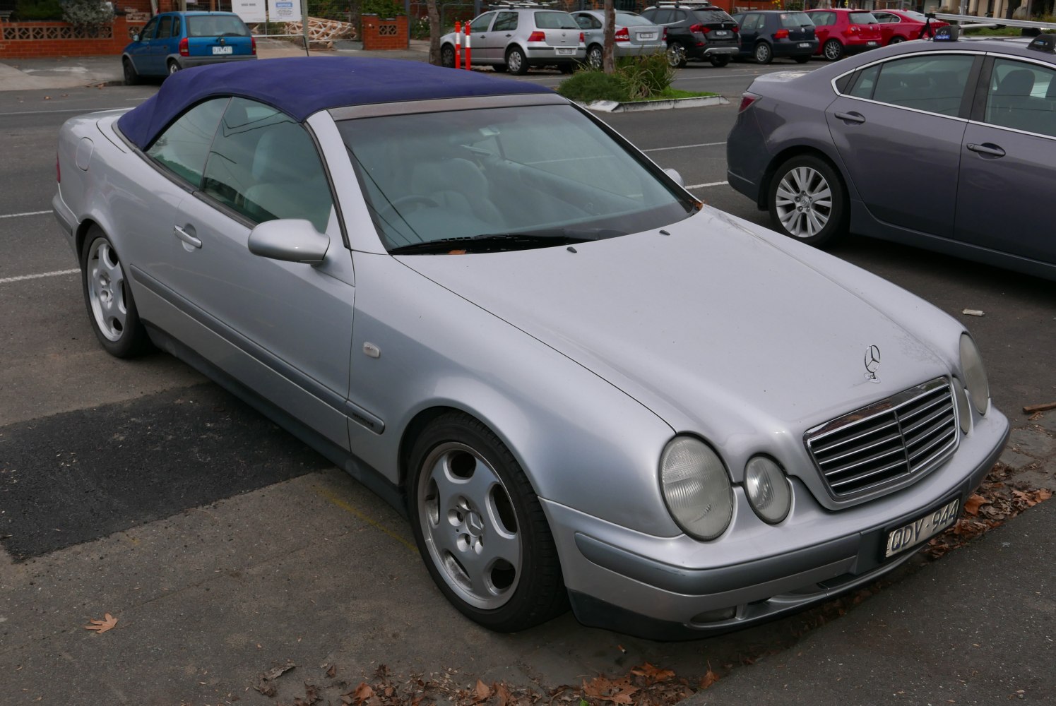 Silver convertible with blue soft top and dual round headlights