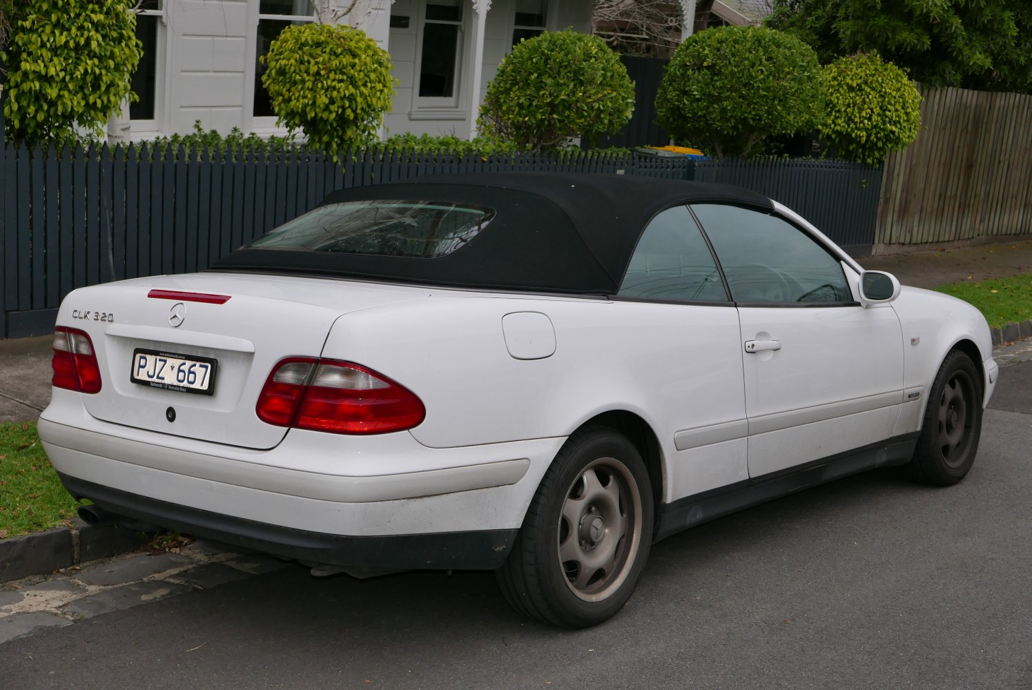 White convertible with soft top, rear view, taillights and emblem visible