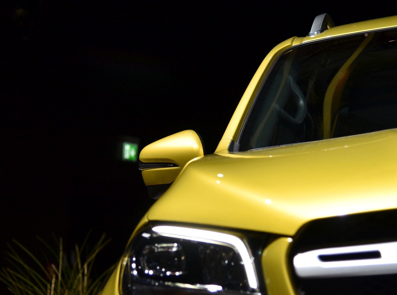 Close-up of front headlight and side mirror on yellow vehicle