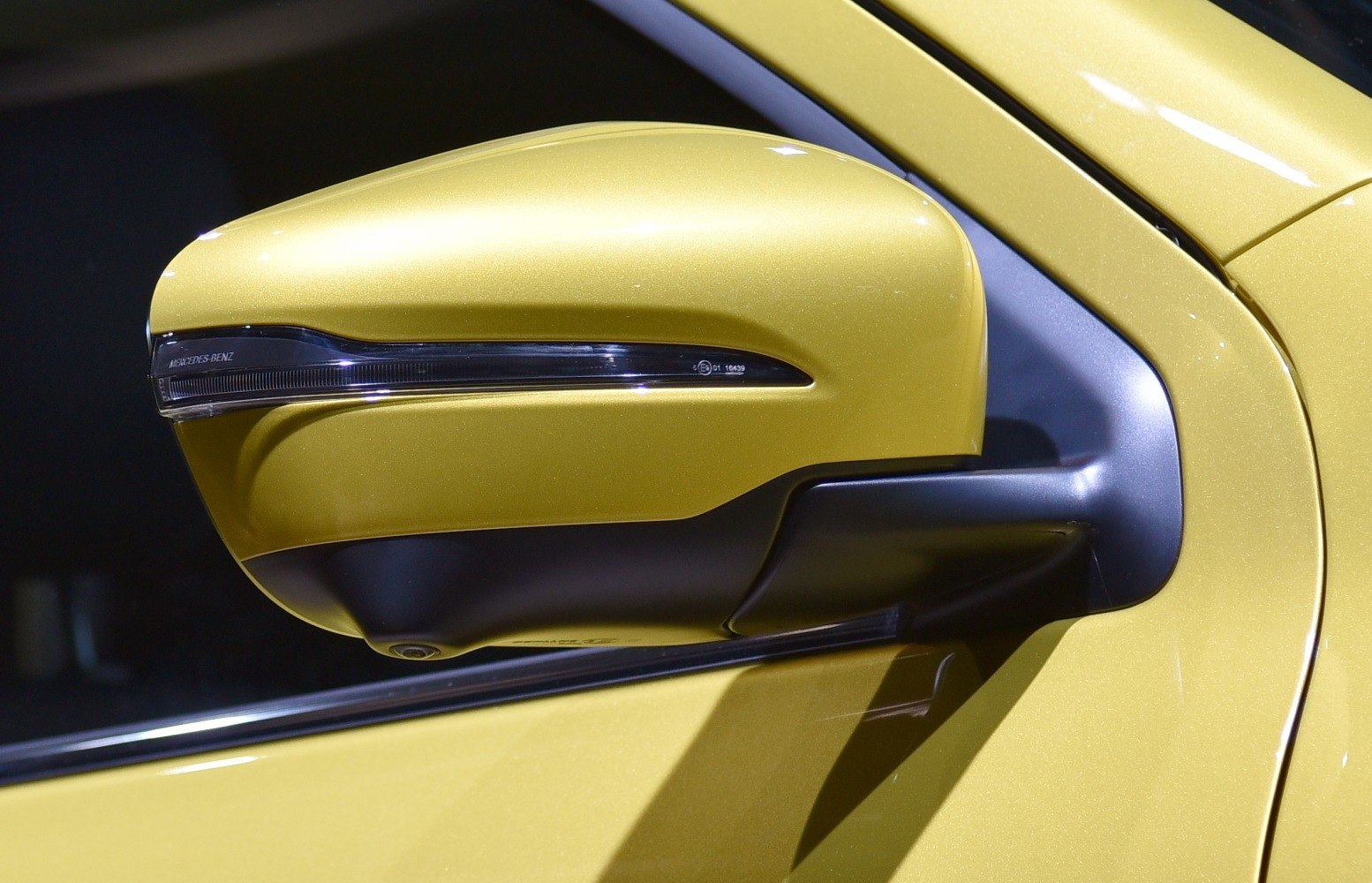 Yellow side mirror with integrated turn signal and camera.